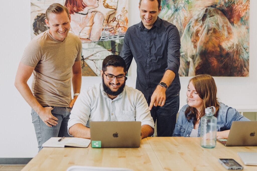 Best Agency Management Software in 2026: 6 Platforms Compared Creative agency team collaborating around a laptop during a project review